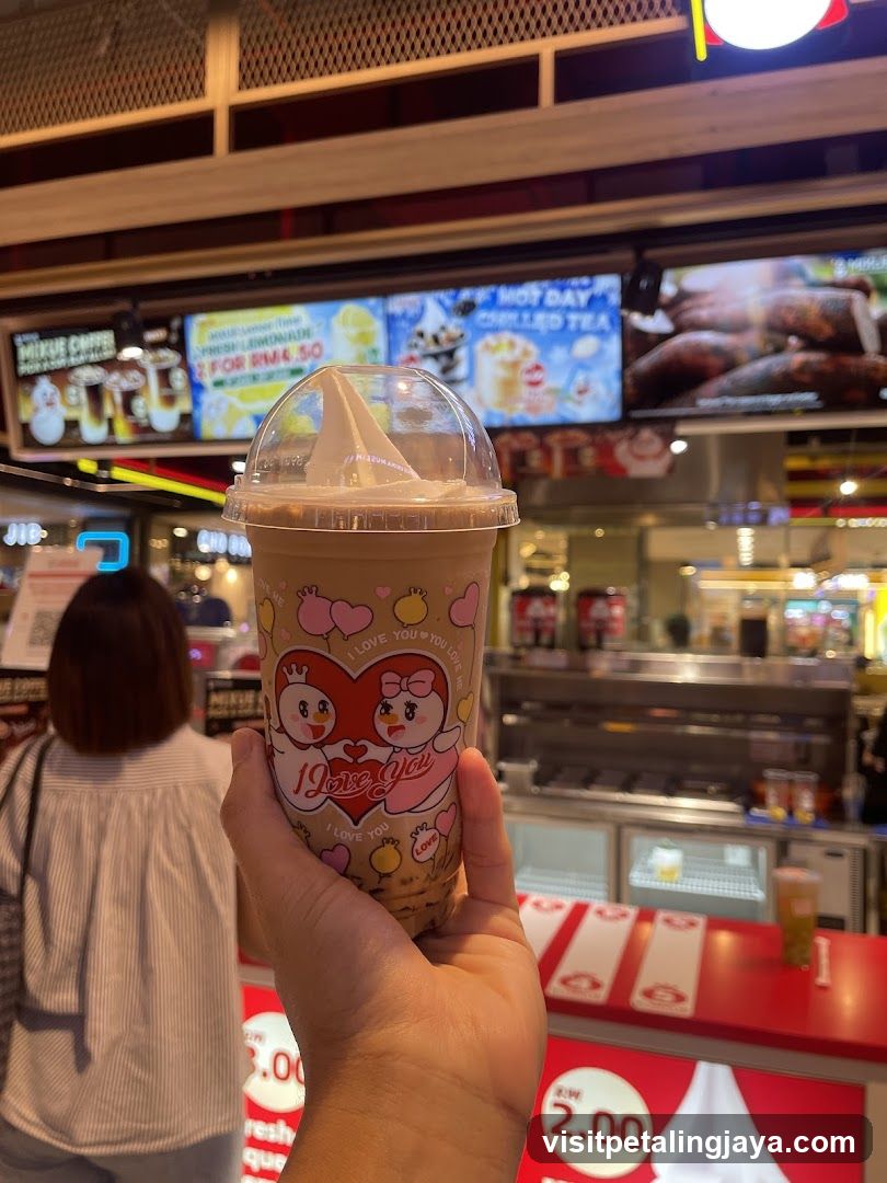Hand holding a beverage cup in a food court