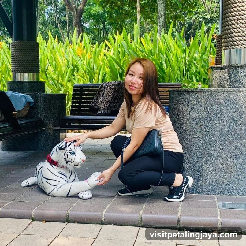 Woman petting a white tiger statue in a park