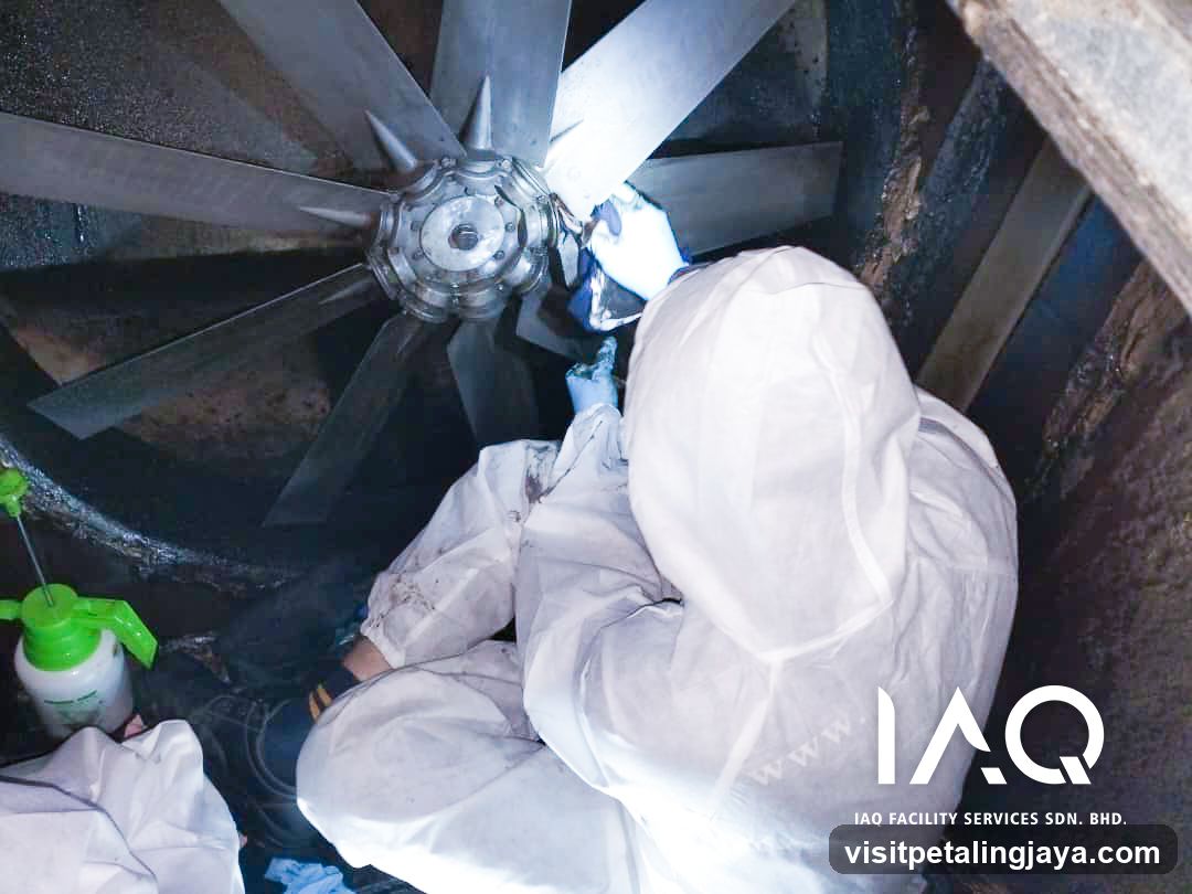 Worker in protective gear cleaning industrial equipment
