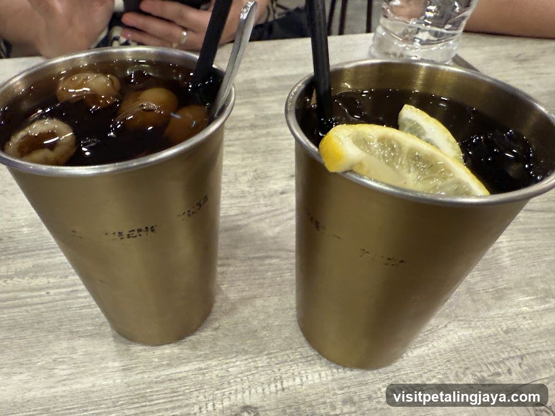 Two metal cups with dark drinks on a table