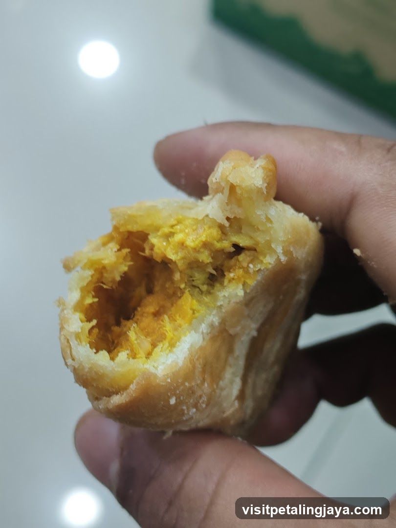 Hand holding a broken pastry with yellow filling