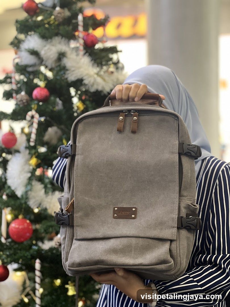 Person holding a backpack near Christmas tree