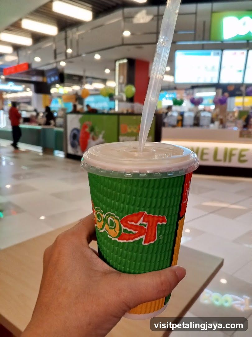 Hand holding a green cup with straw in mall
