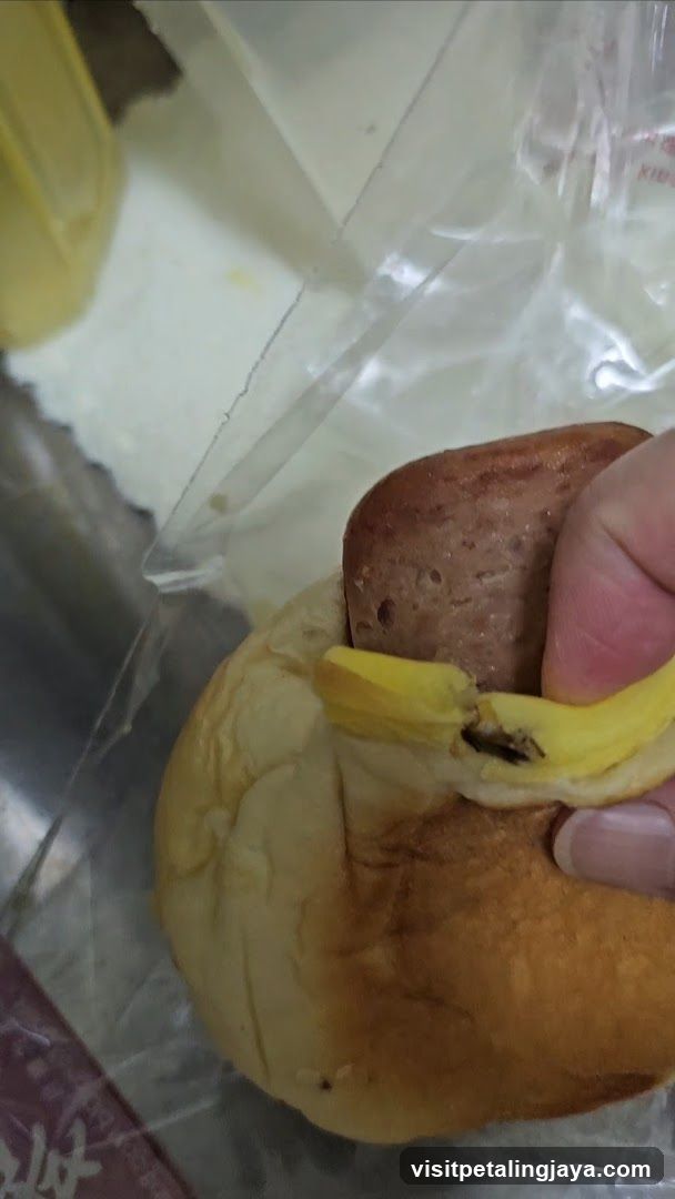 Hand holding a bun with banana and sausage
