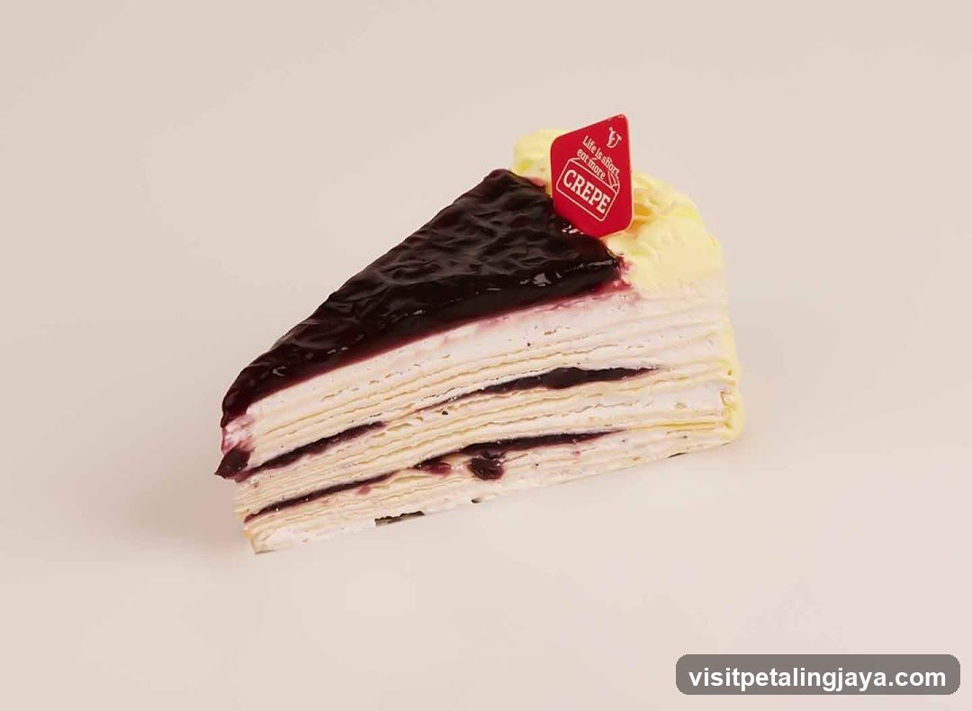 Slice of layered crepe cake with berry topping