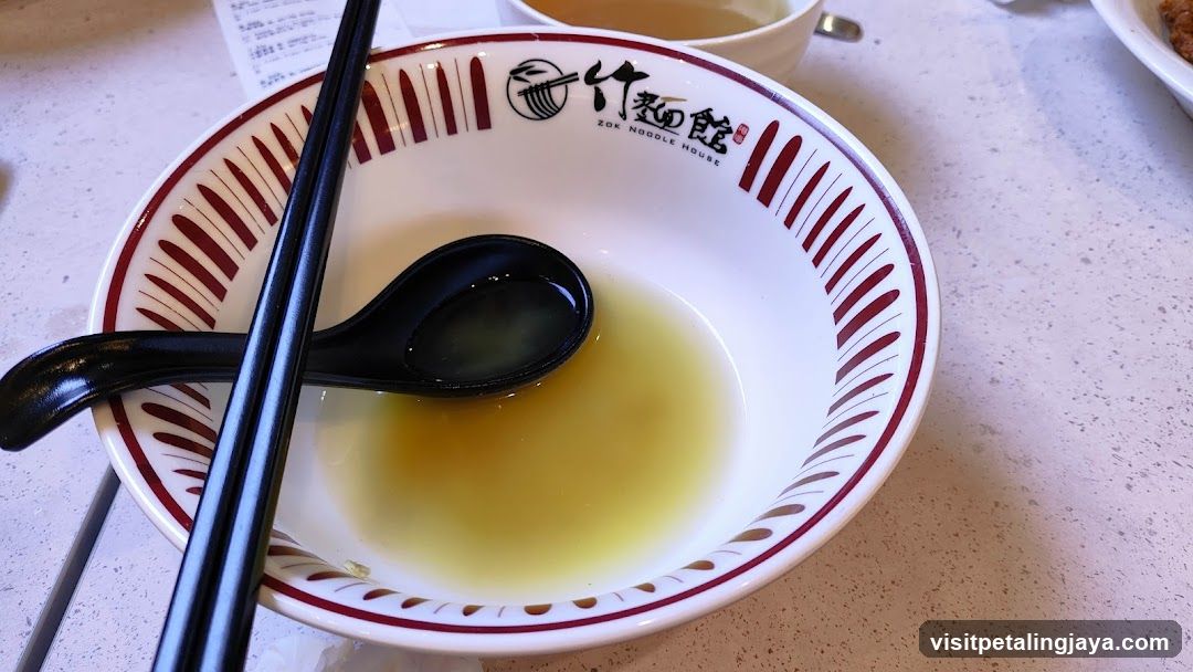 Bowl of broth with chopsticks and spoon