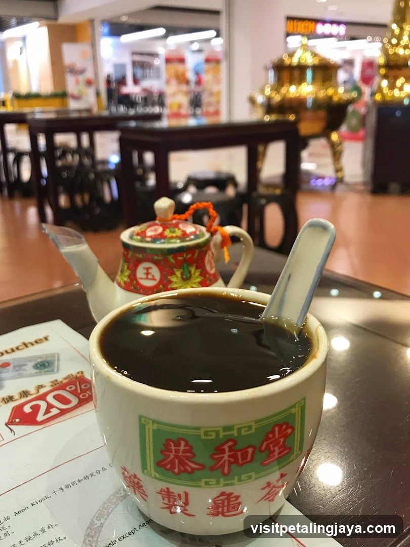Bowl of dark soup with teapot in restaurant interior