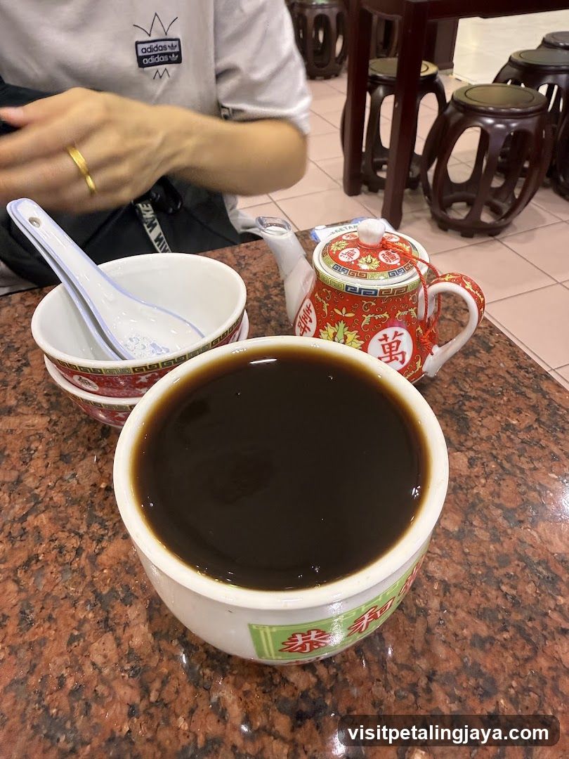 Bowl of dark liquid with teapot and spoon